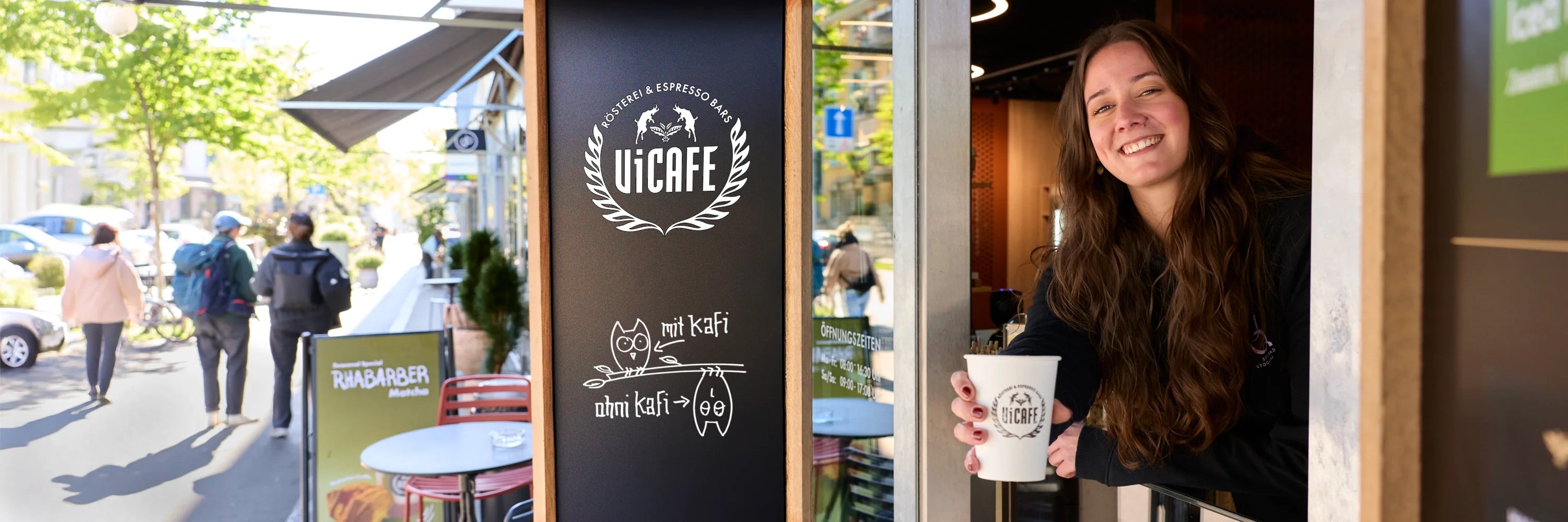 Barista serviert Cappuccino mit Latte Art im ViCAFE Espresso Bar Fenster in Zürich – Spezialitätenkaffee aus frisch gerösteten Kaffeebohnen